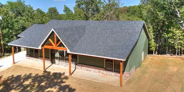 Image 4: Exterior featuring green siding, a gable roof with