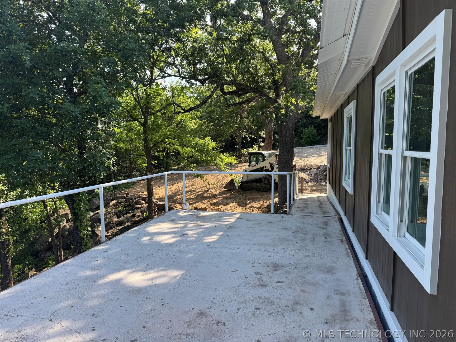 Image 3: Concrete patio with white railing and brown siding