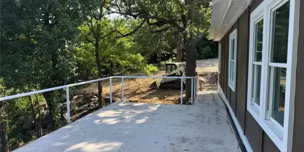 Image 3: Concrete patio with white railing and brown siding