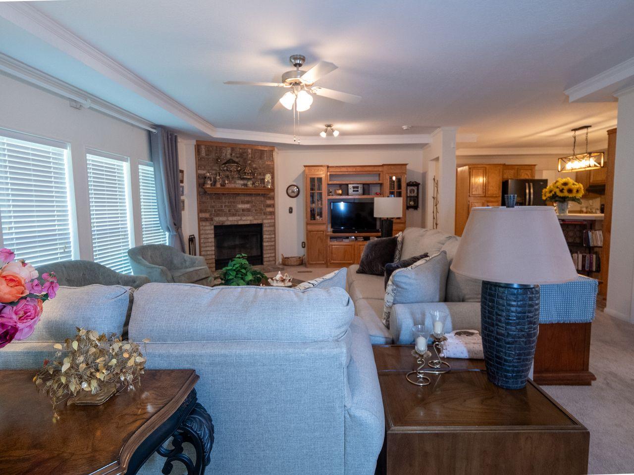 Image 3: Living area featuring a brick fireplace with a woo