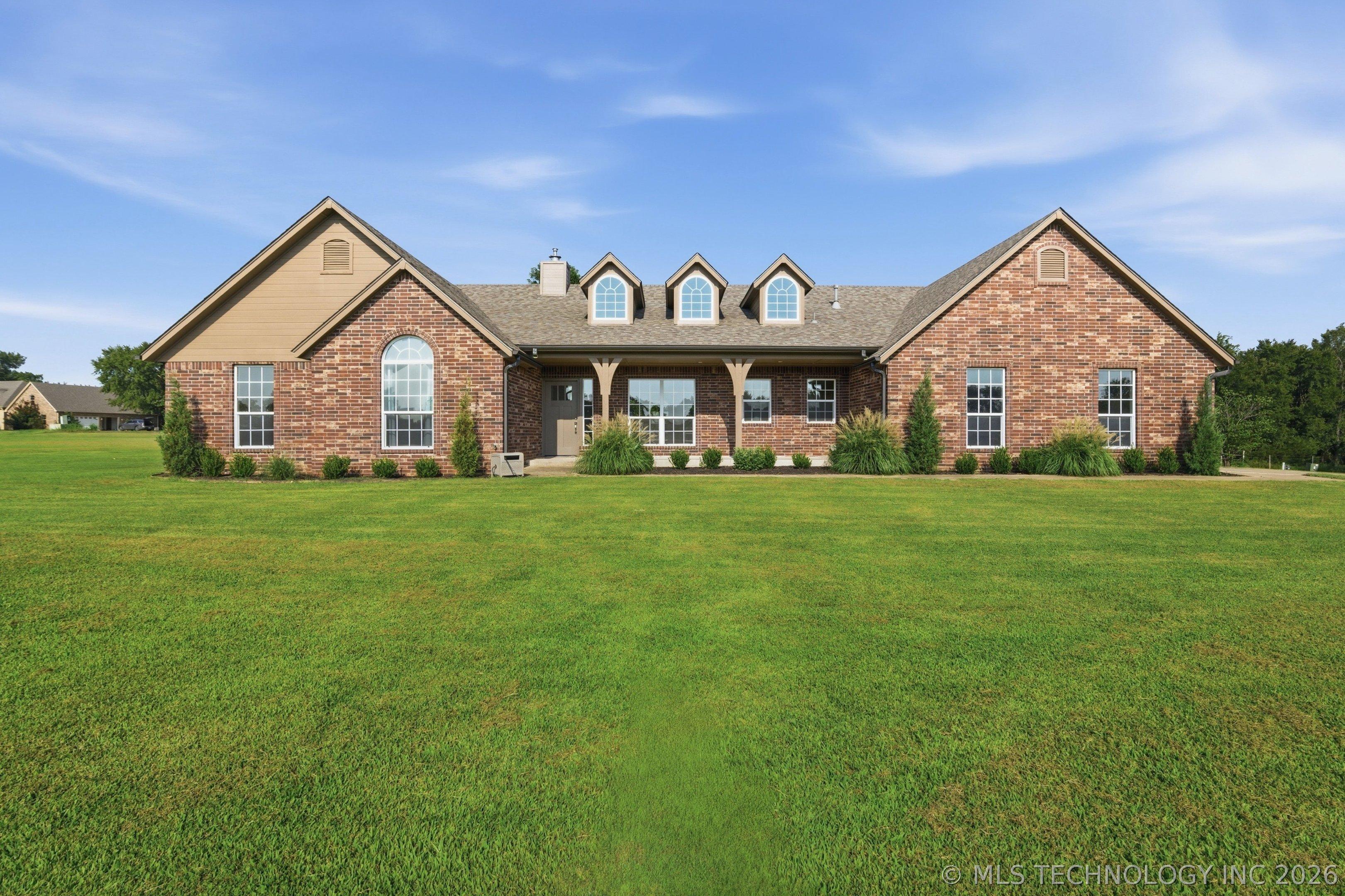 Image 4: Expansive front lawn with a brick exterior and dor