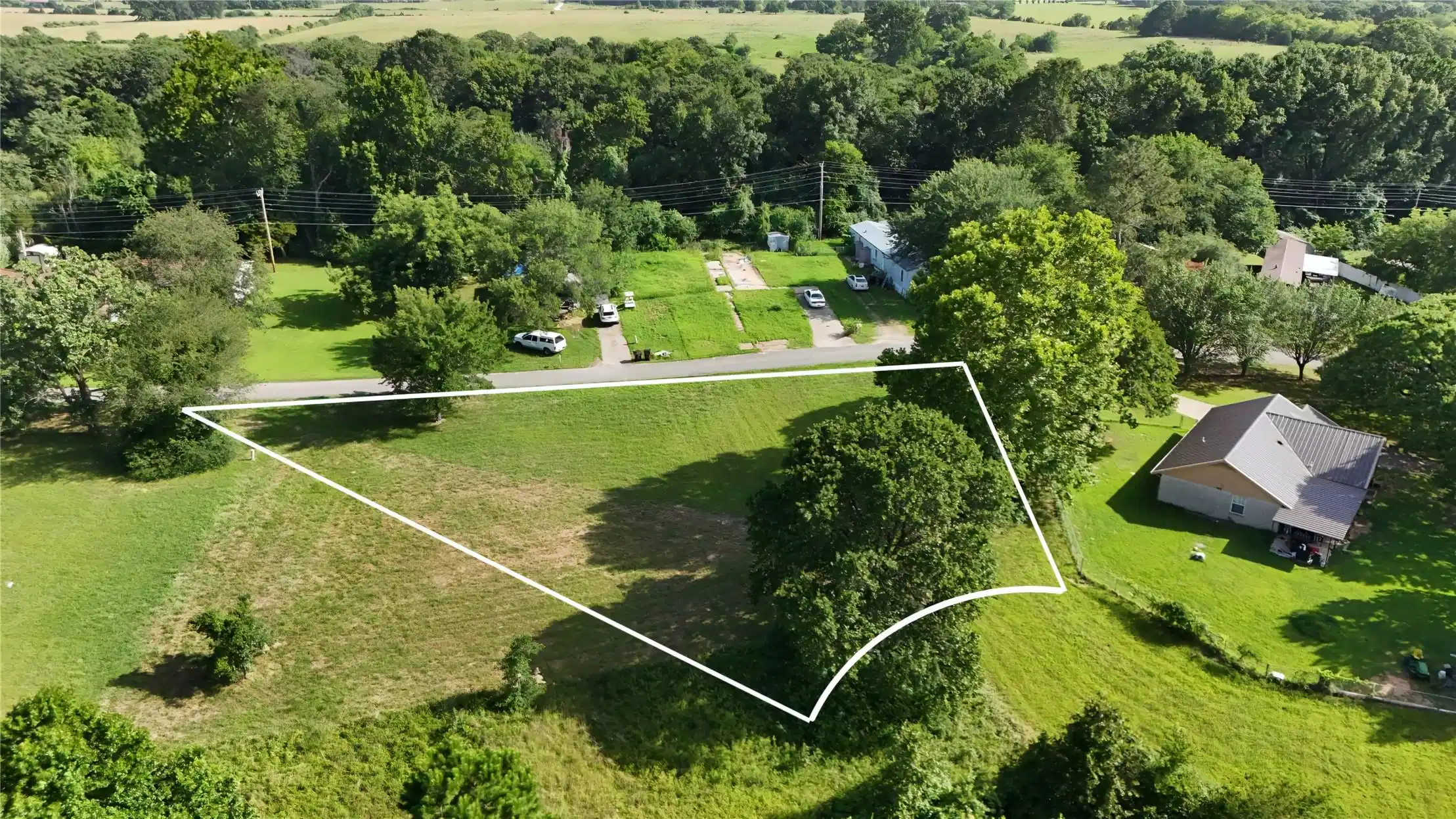Image 1: Expansive grass lot featuring mature trees and a s
