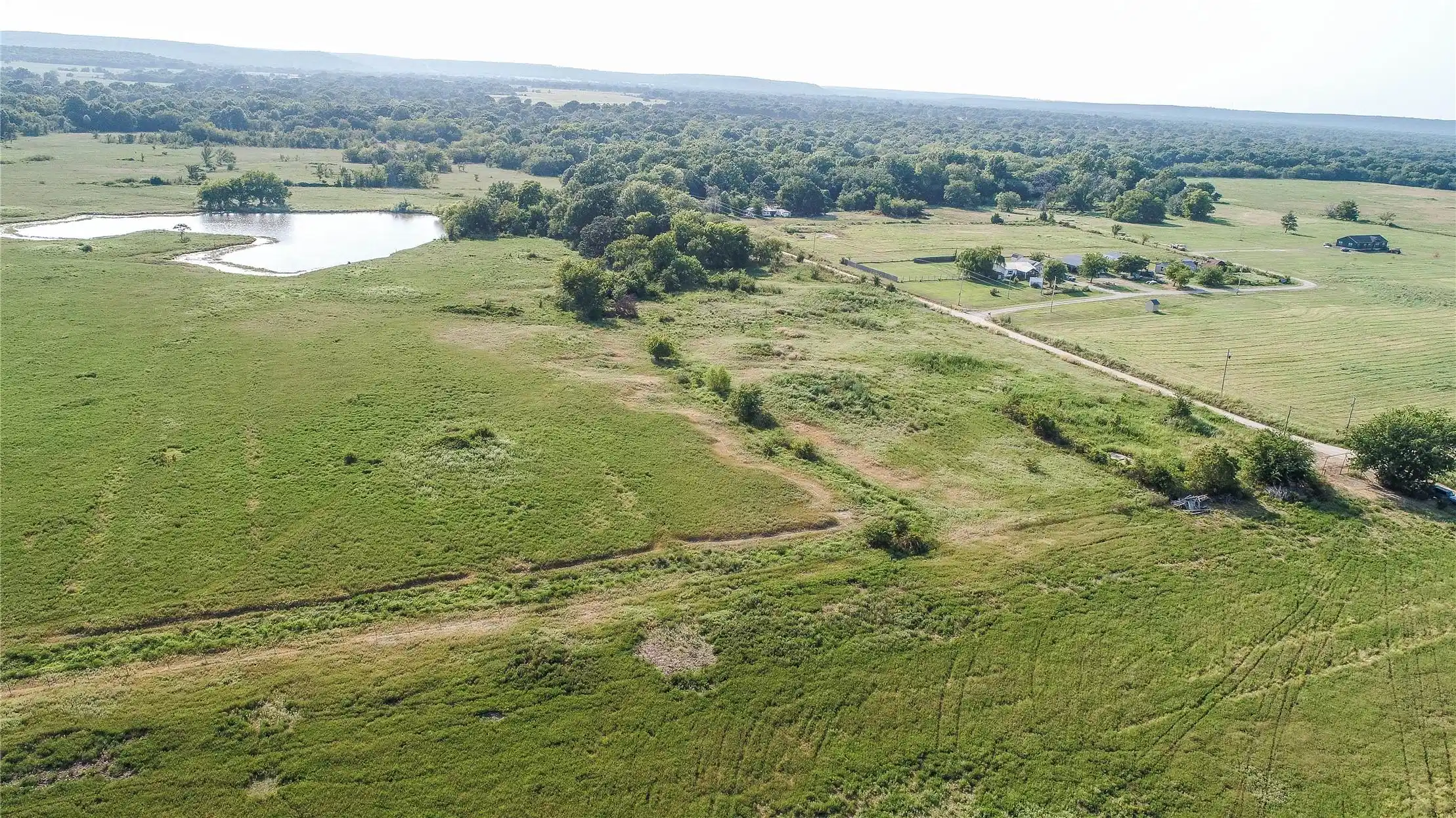 Image 1: Expansive land featuring a natural pond, lush gree