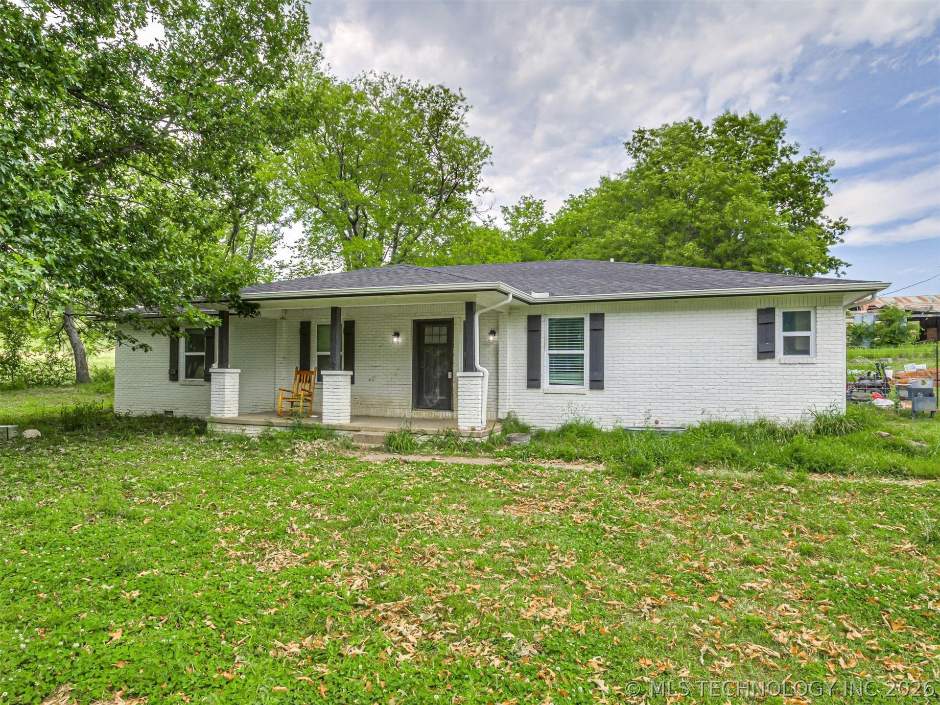 Image 1: White brick exterior featuring a covered porch wit