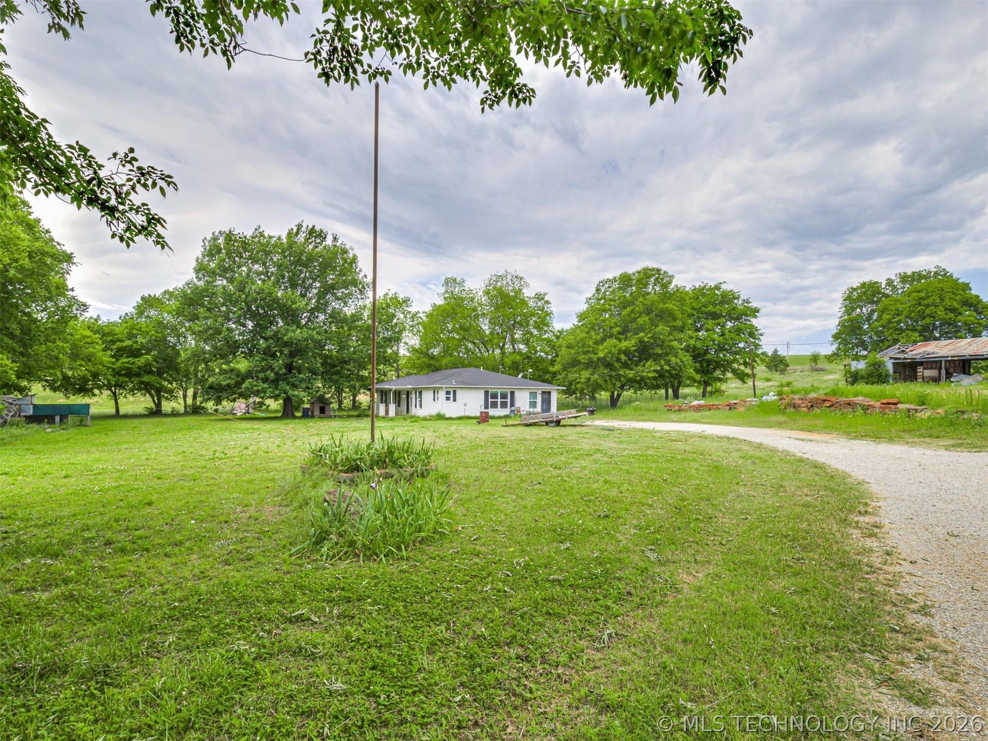 Image 4: Expansive green lawn surrounds a single-story whit