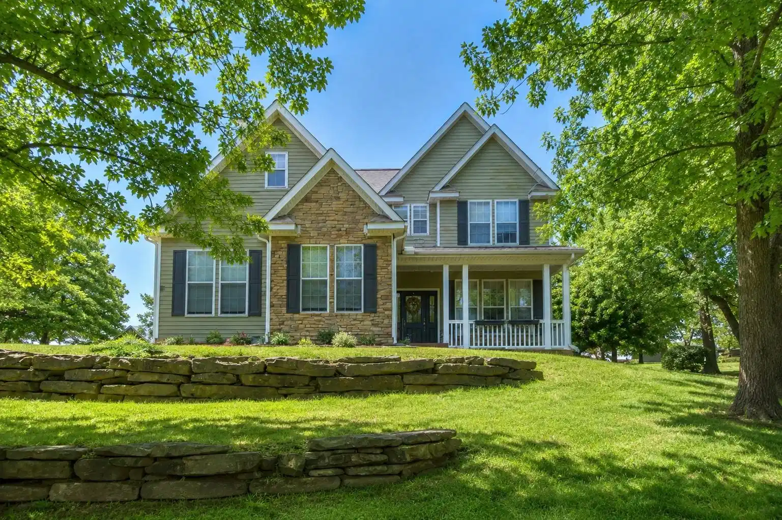 Image 1: Two-story residence featuring a stone and siding e