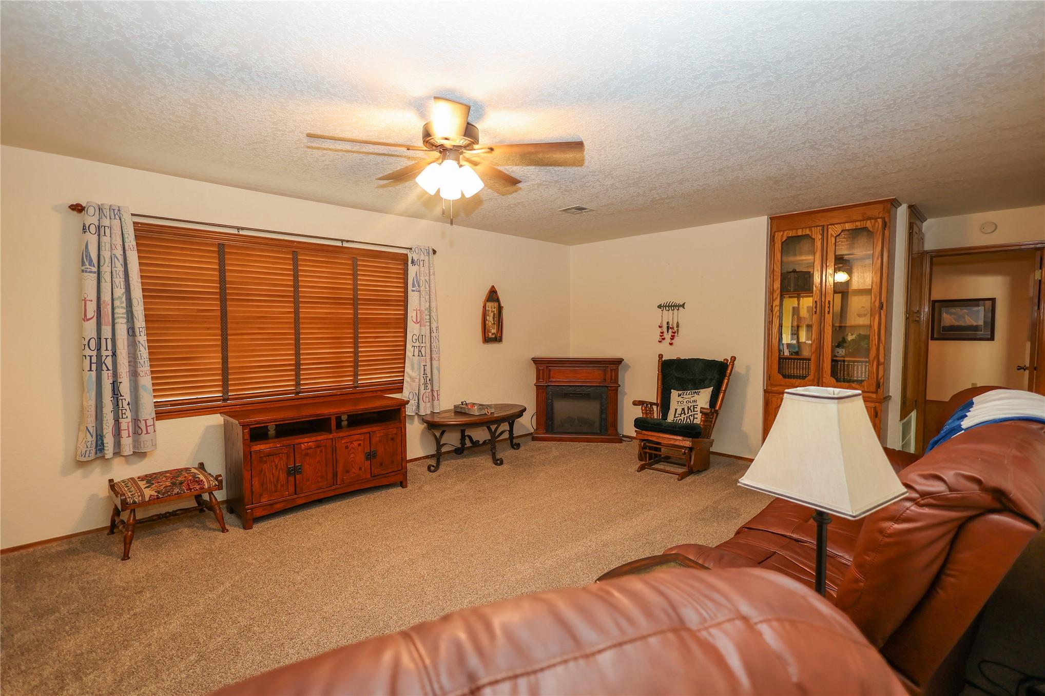 Image 3: Carpeted living area featuring a ceiling fan with