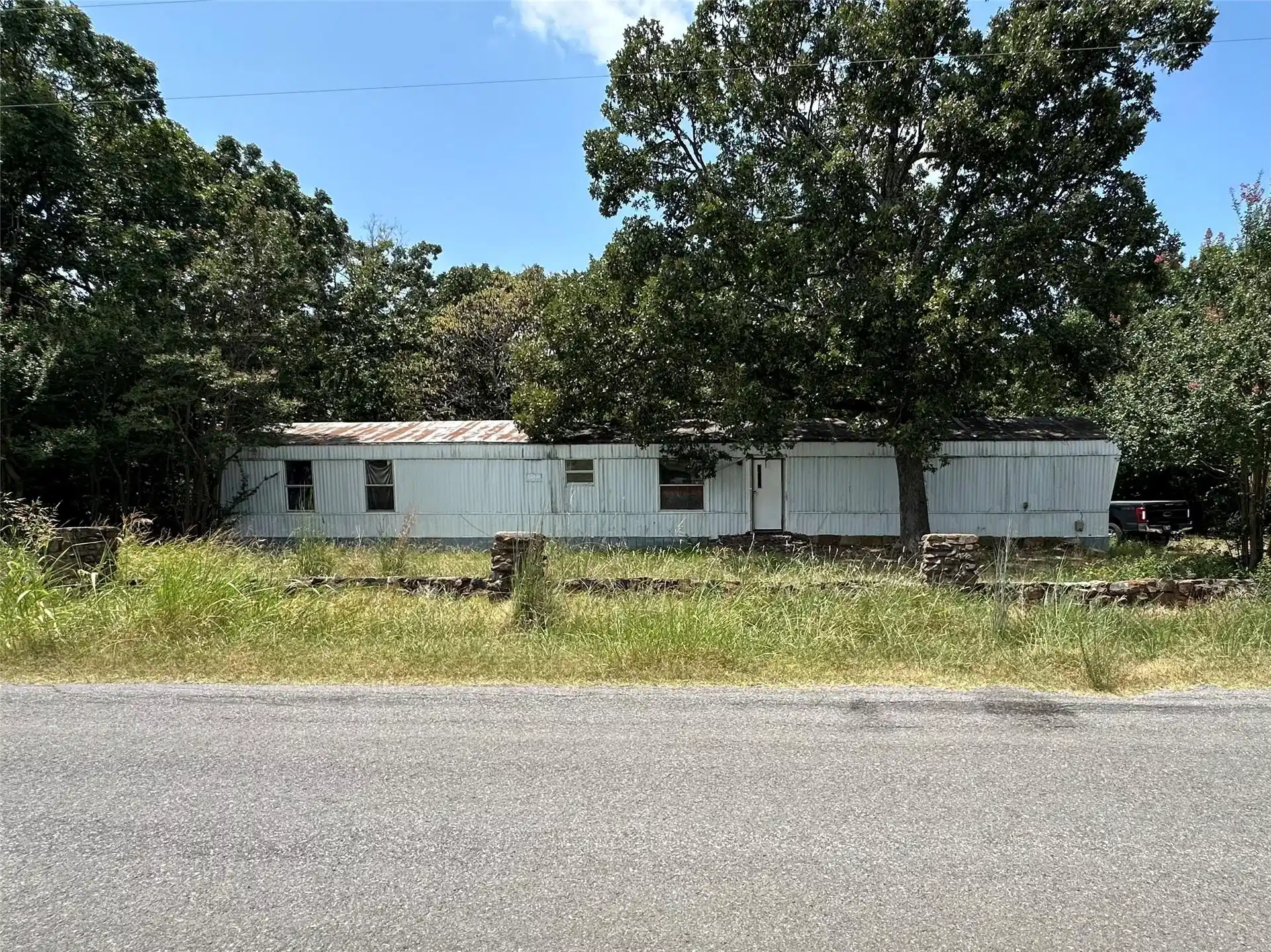 Image 1: Single-story white manufactured home surrounded by