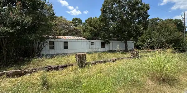 Image 2: White siding structure with multiple windows, surr