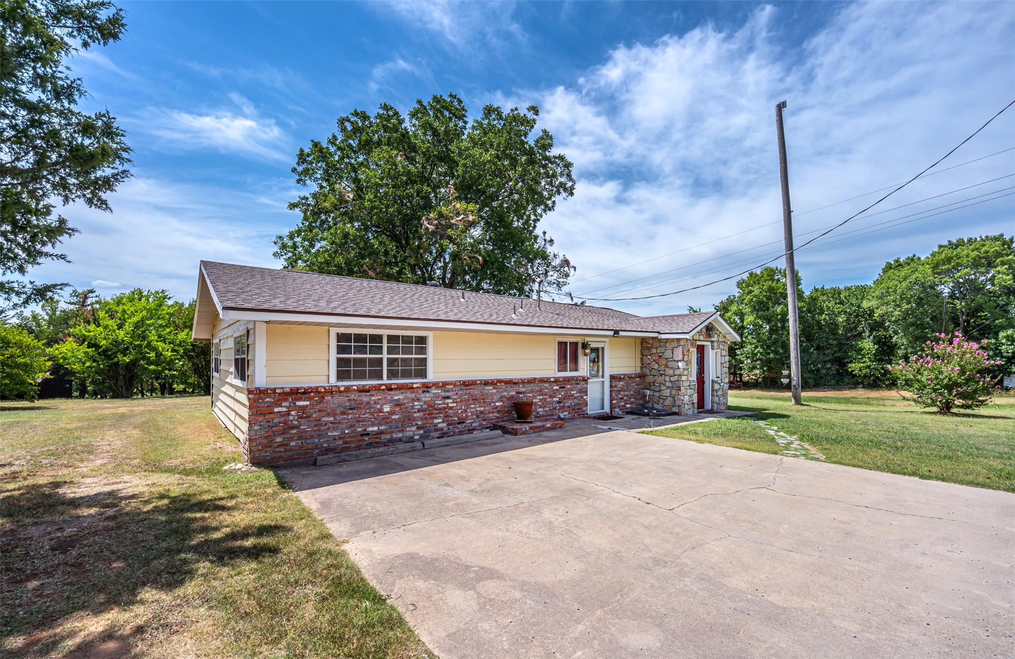 Image 2: Ranch-style exterior featuring yellow siding, a br