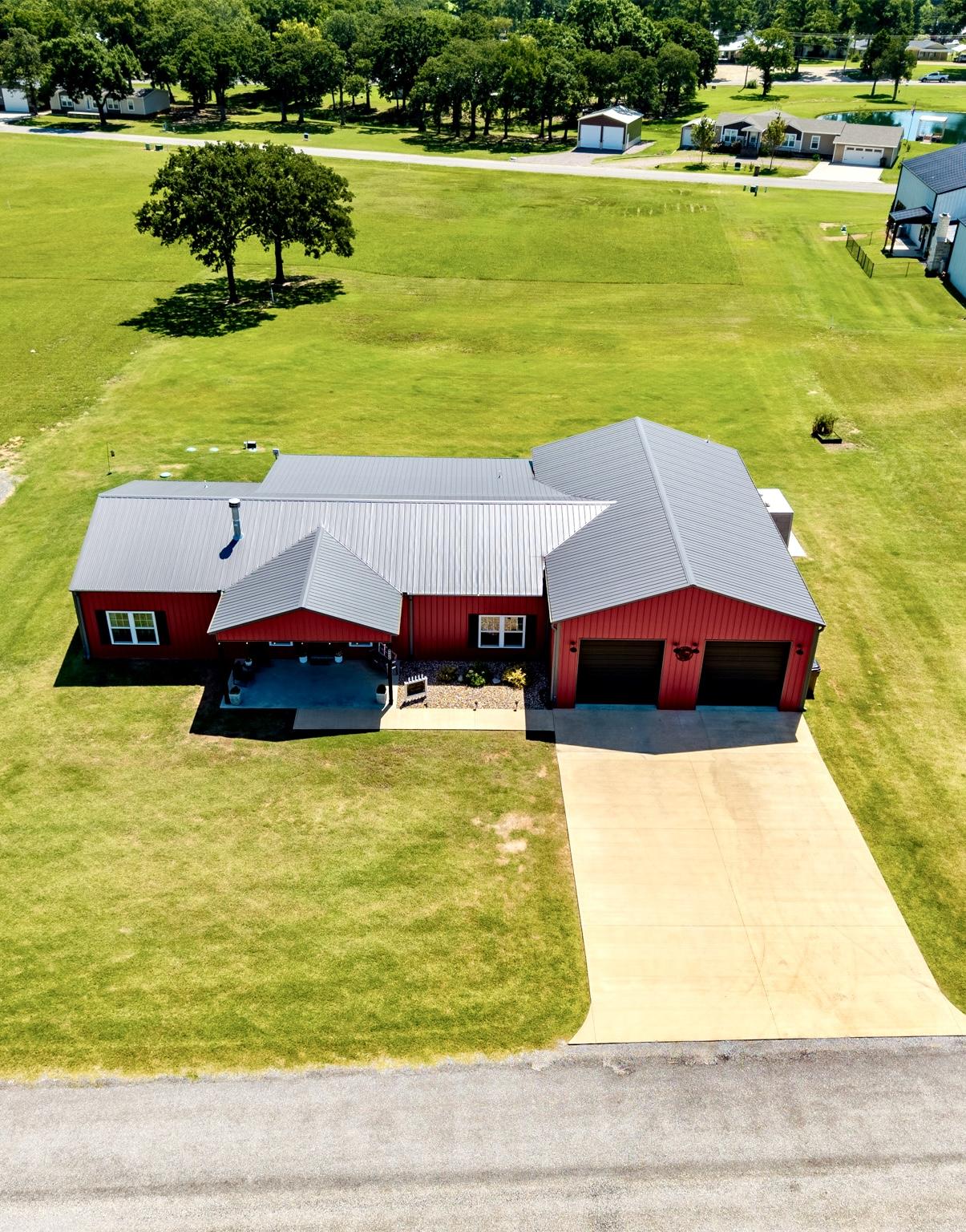 Image 2: Red-sided residence featuring a gray metal roof an