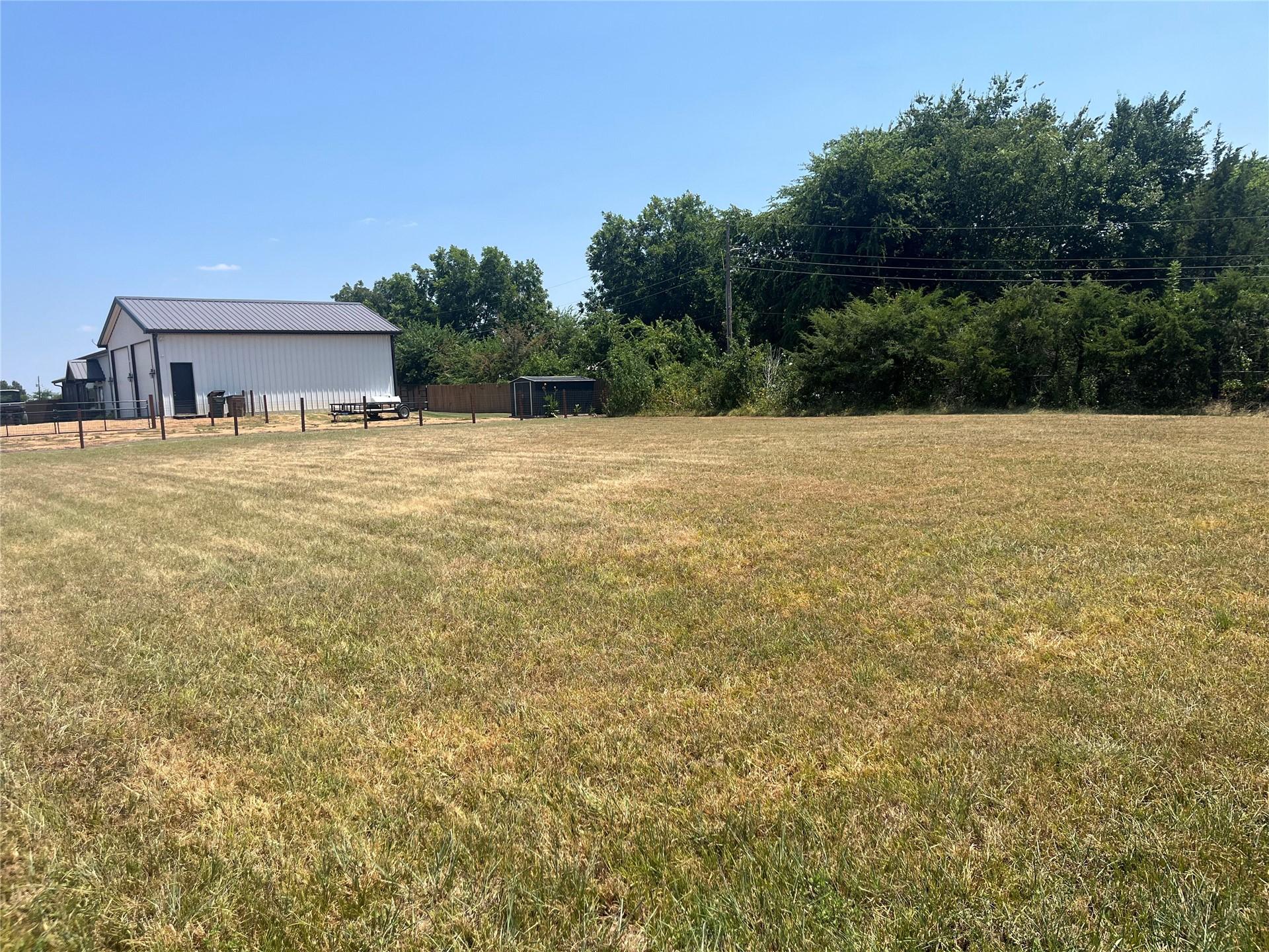 Image 1: Expansive cleared lot with a white barn featuring