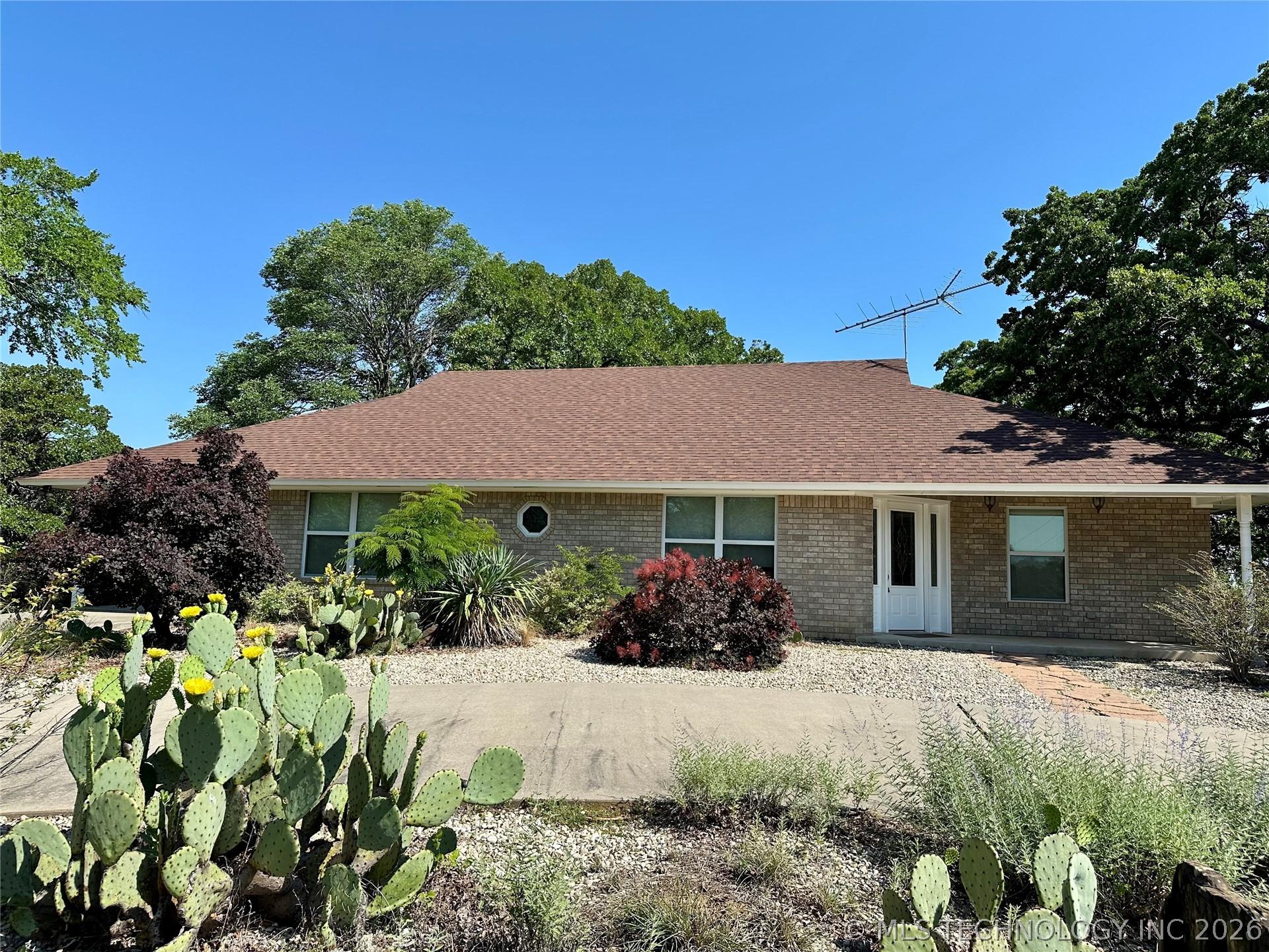 Image 2: Brick exterior with a brown shingle roof, featurin