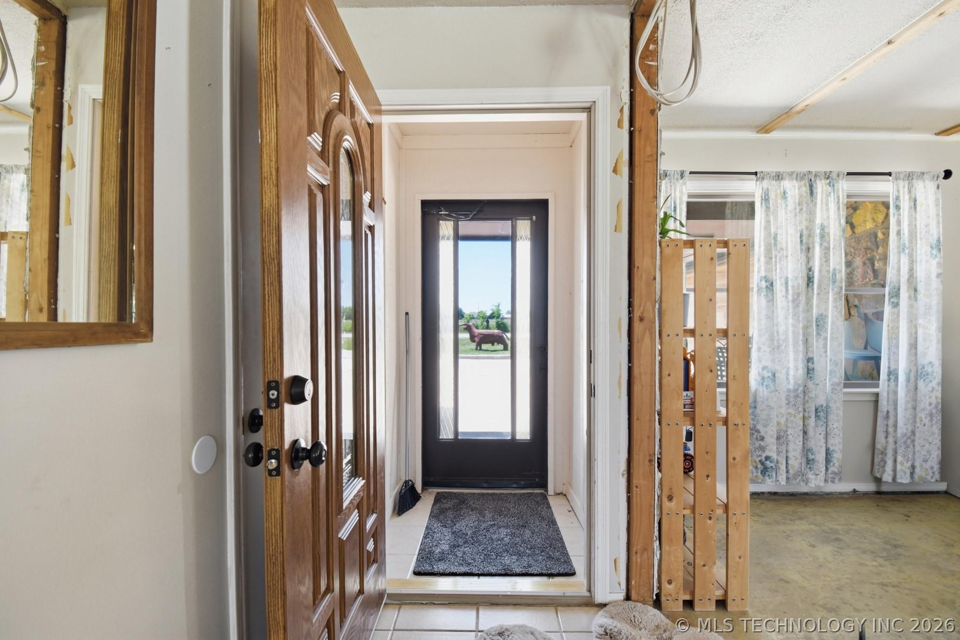 Image 4: Wood-paneled entry door with dark hardware opens t