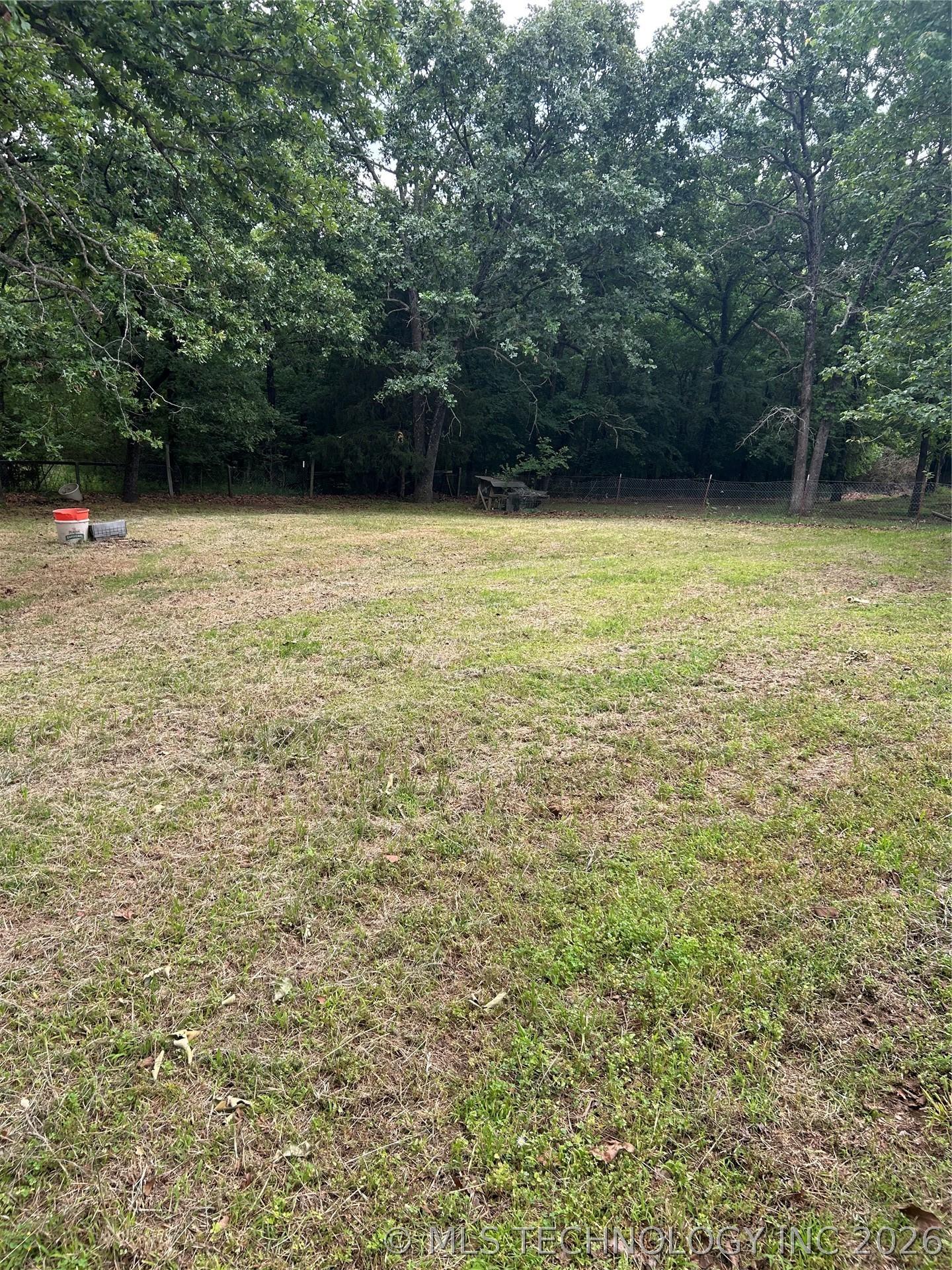 Image 4: Expansive yard space with mature tree backdrop and