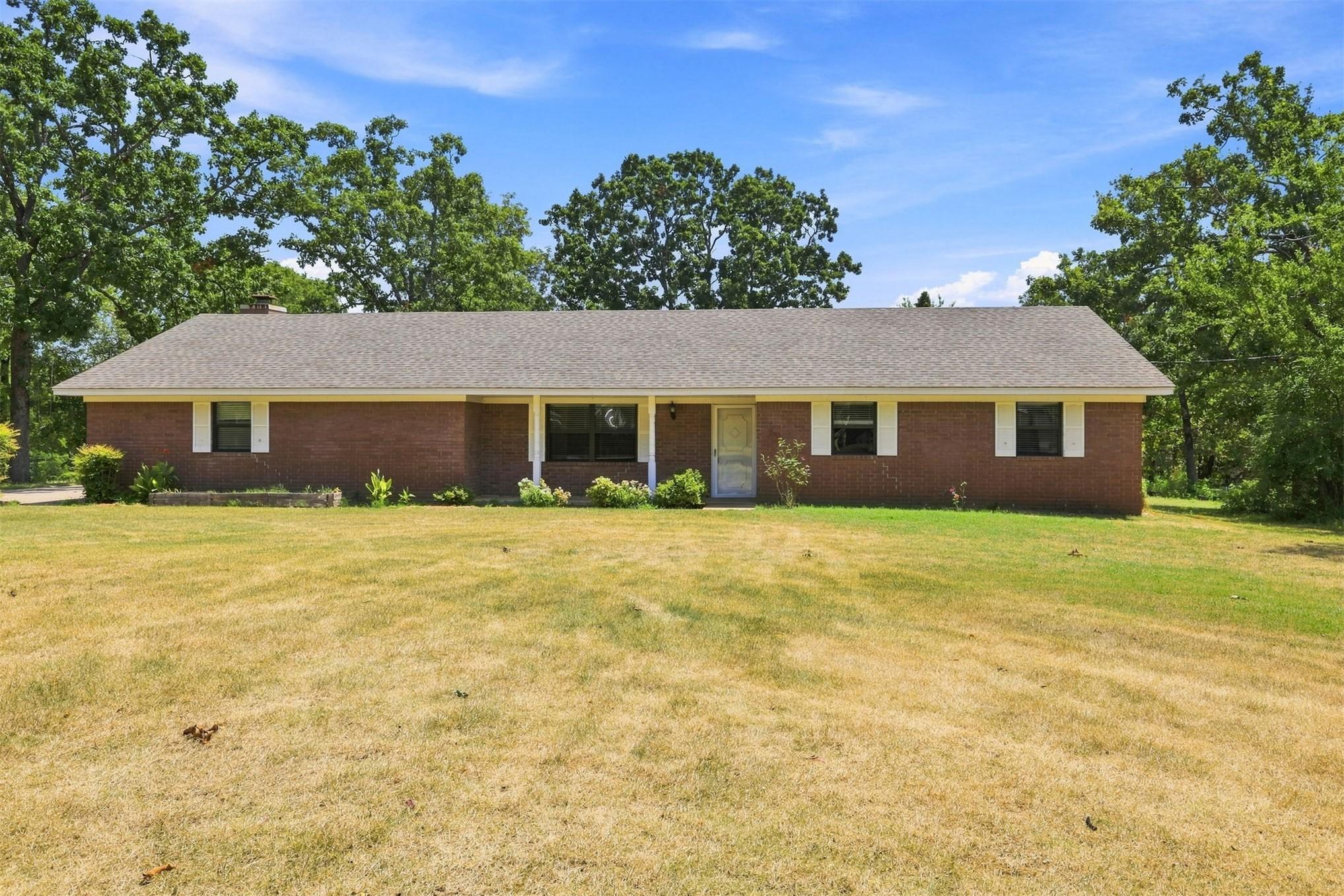 Image 2: Brick ranch-style home featuring a gray shingle ro