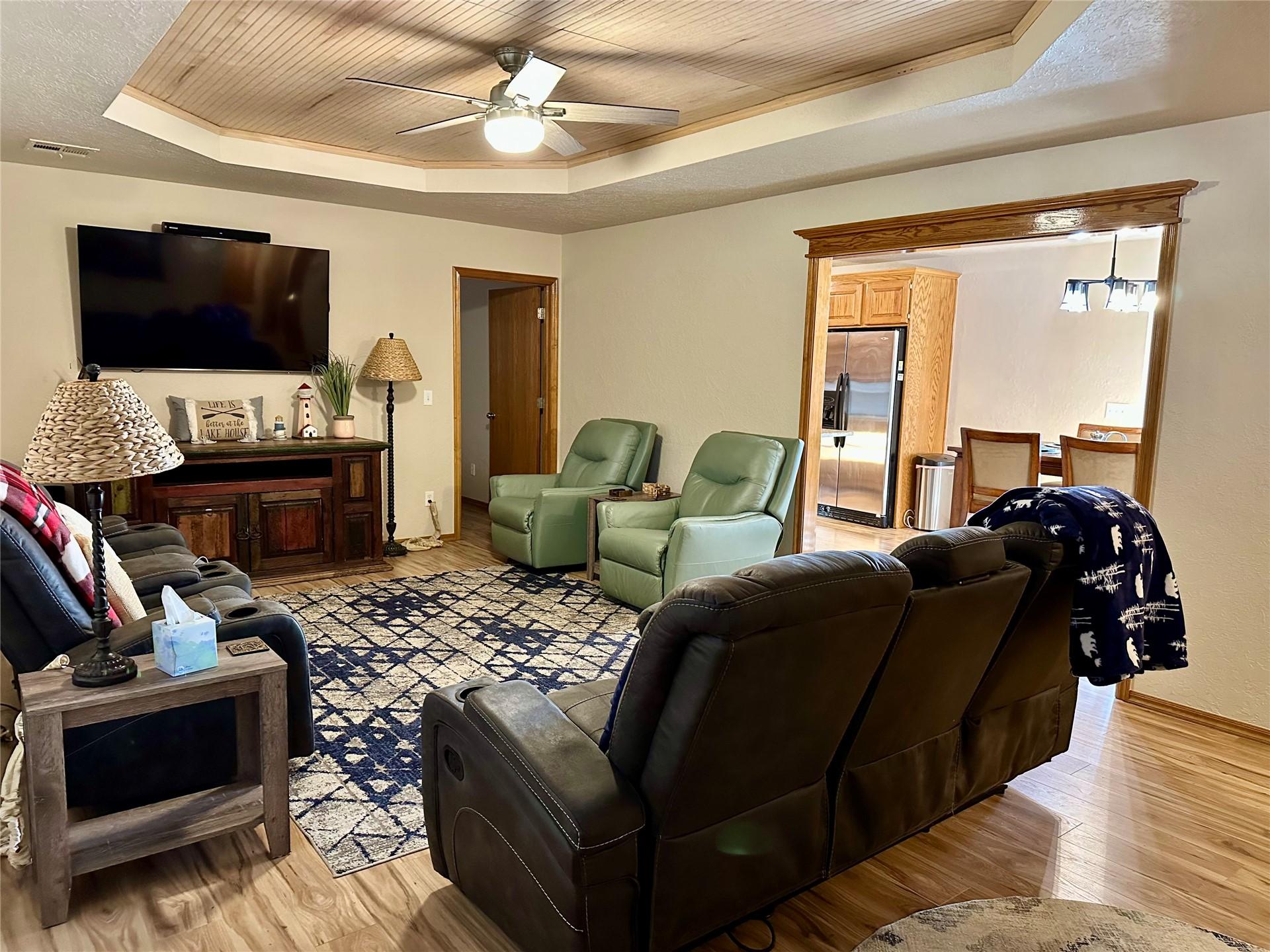 Image 2: Living area with wood-finish flooring, a tray ceil