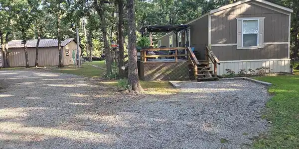 Image 3: Gravel driveway leading to a brown-sided residence
