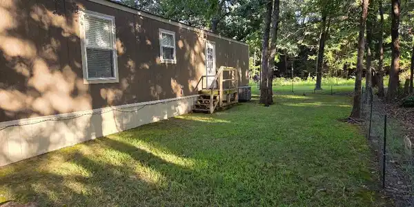Image 4: Expansive grassy yard with mature trees and a peri