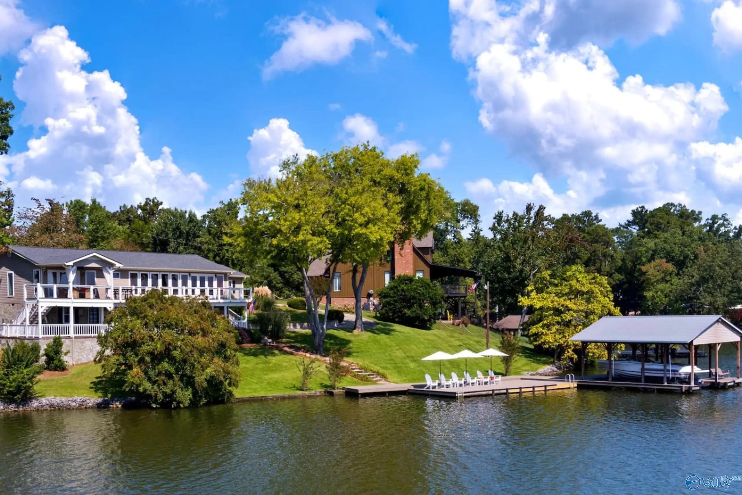 Image 2: Welcome to your lakeside retreat with private dock, lounge area and boathouse with two jet ski lifts and boat lift. Surrounded by mature trees and well-kept lawns, offering a serene setting for relaxation and outdoor living.