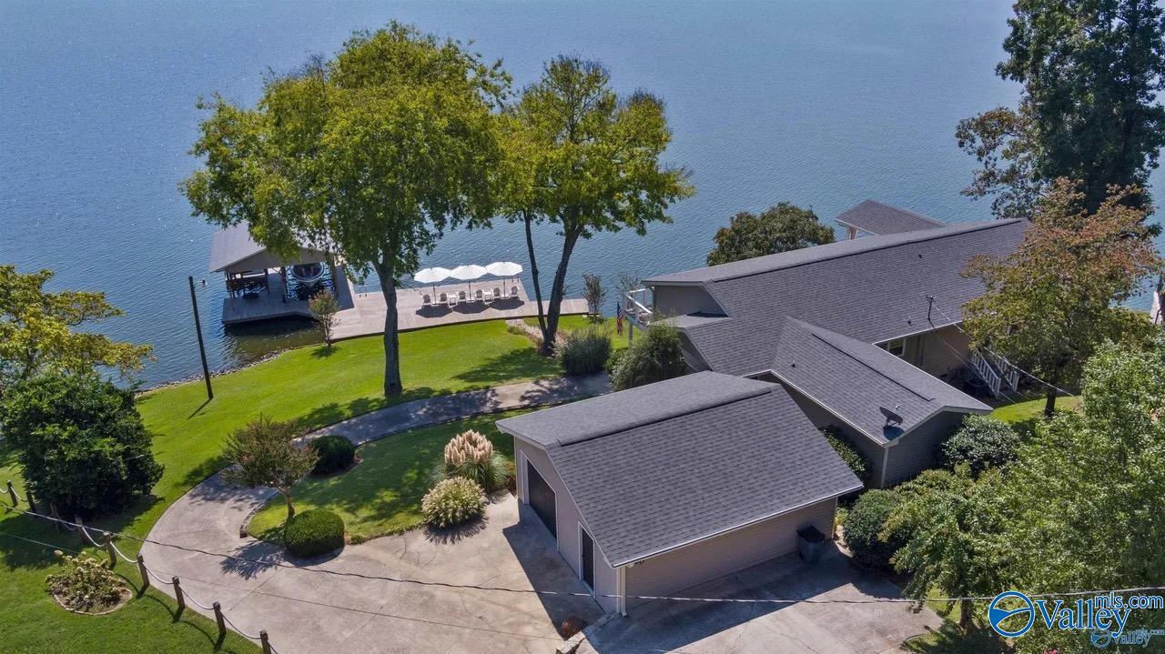 Image 3: Home sits right at the shoreline, offering immediate access to the lake and a scenic setting perfect for outdoor living. Picture features overhead of main home and detached 1.5 car garage and workshop.