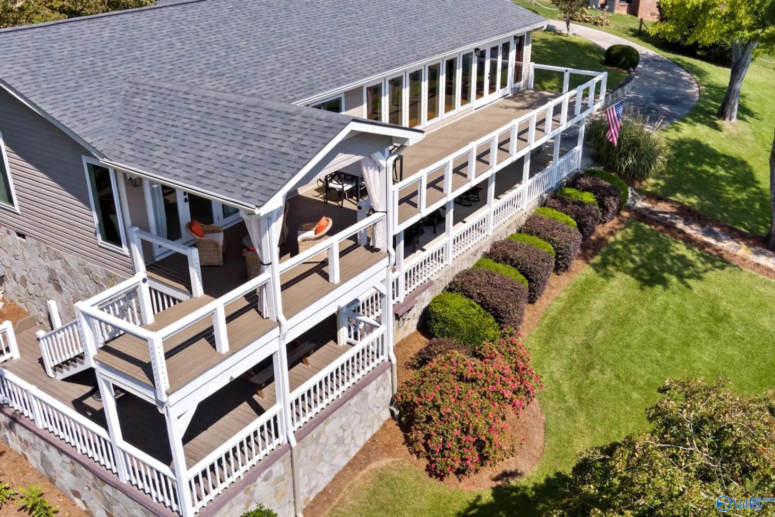 Image 4: Home features upper and waterfront porches, stone accents, and manicured landscaping. Large windows, inviting outdoor spaces, and a well-kept lawn create a warm, welcoming setting