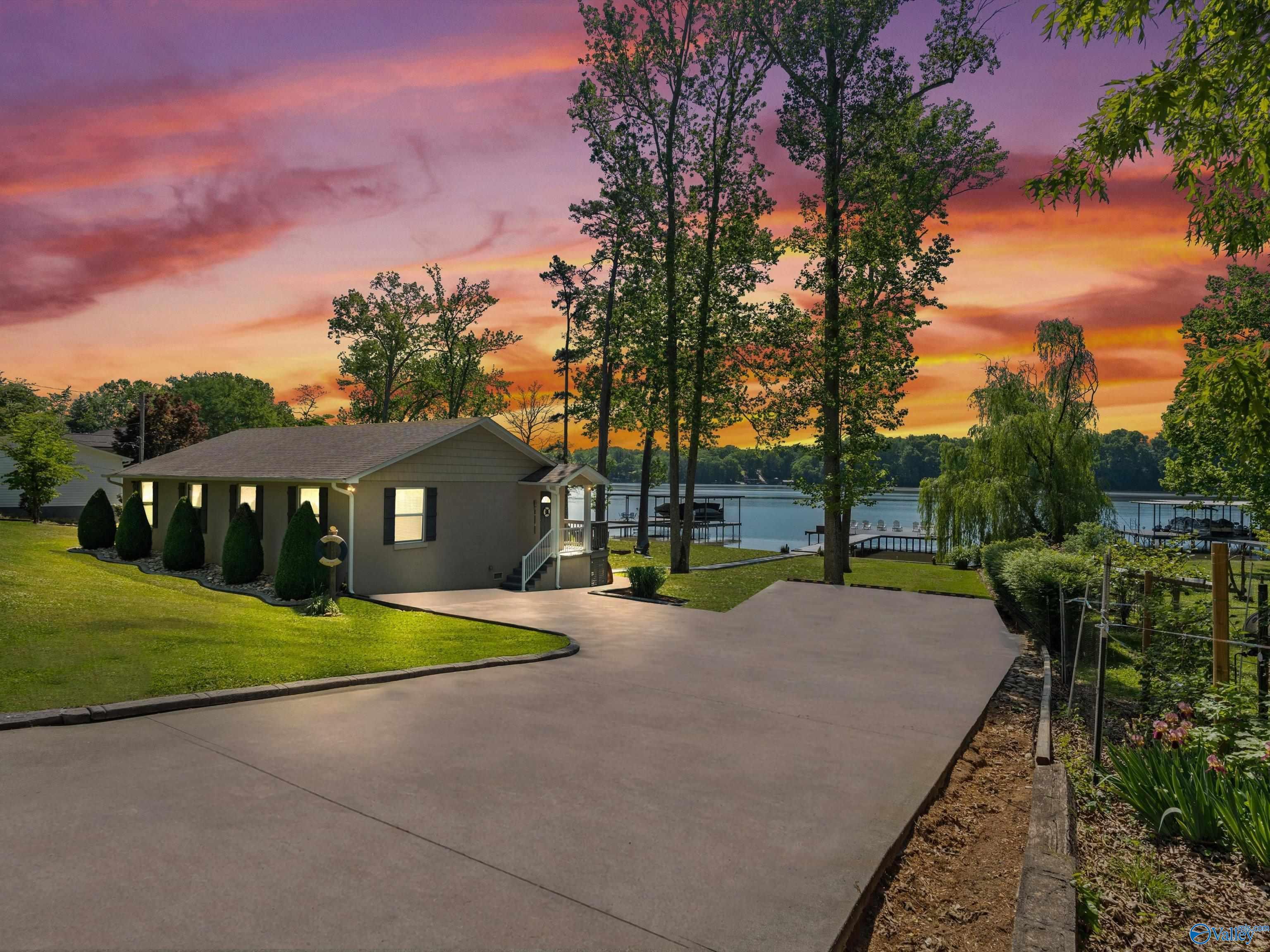 Image 2: stucco house, beautifully landscaped, concrete driveway, gutters, covered home entry, boat dock, some mature trees for shade