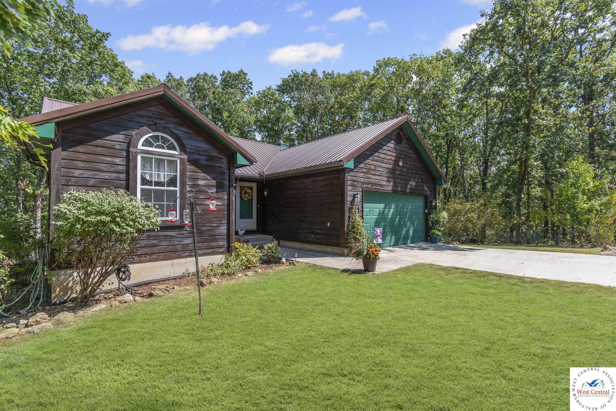 Image 1: View of front of home with a front yard, a garage, driveway, and a metal roof