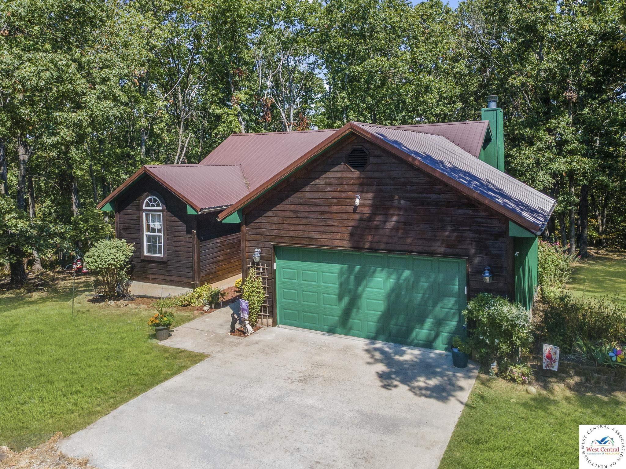 Image 2: View of front of house with a front yard, a metal roof, driveway, and an attached garage