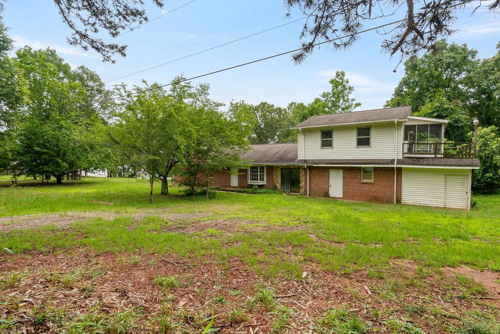 Image 1: Mature trees and a lush lawn envelop this charming