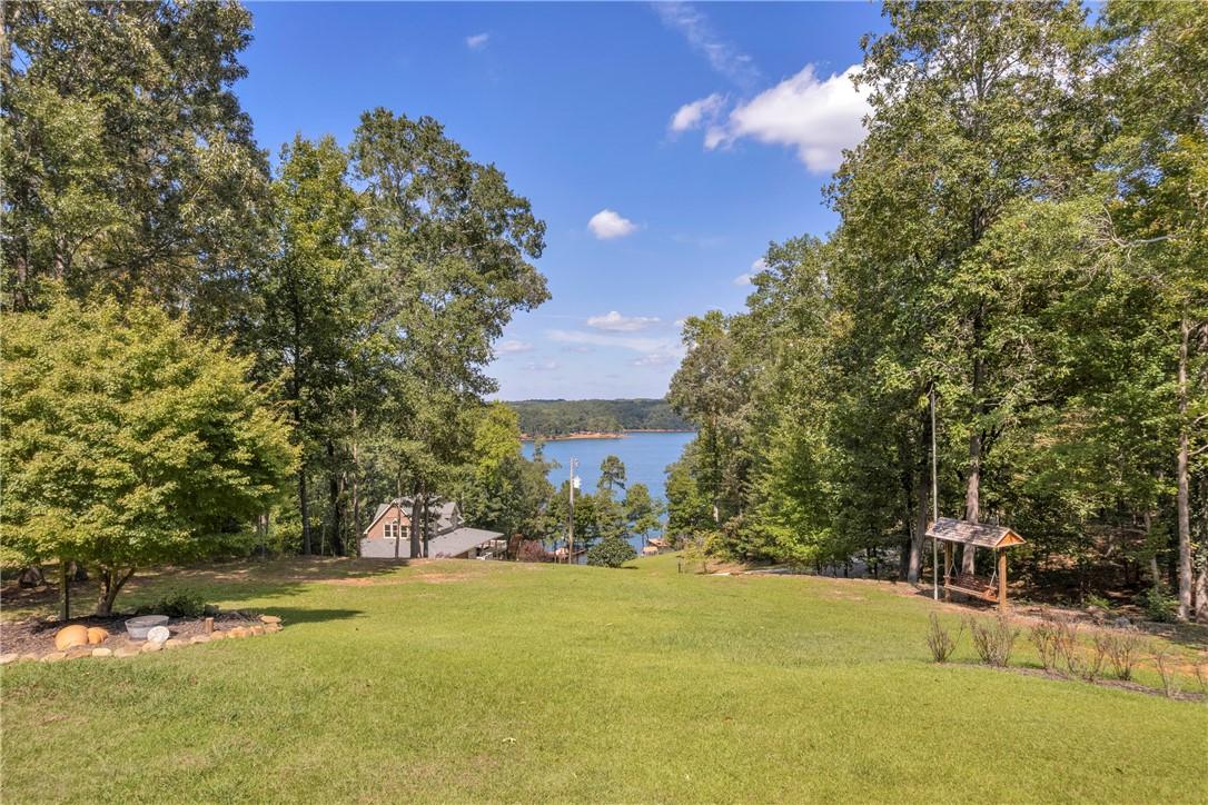 Image 2: A spacious lawn unfolds towards a sparkling lake,