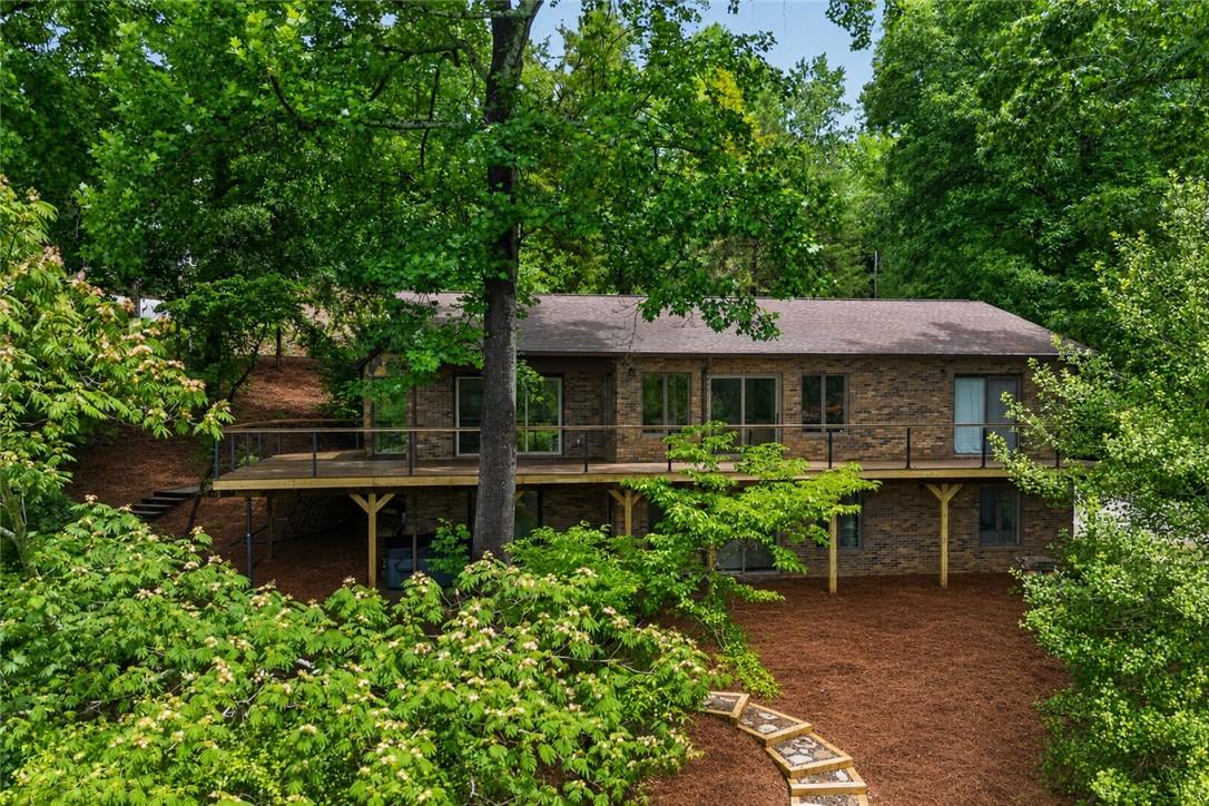 Image 1: Perched among verdant trees, this brick dwelling f