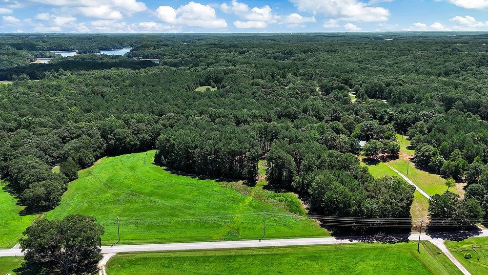 Image 2: Expansive green acreage unfolds with a distant lak