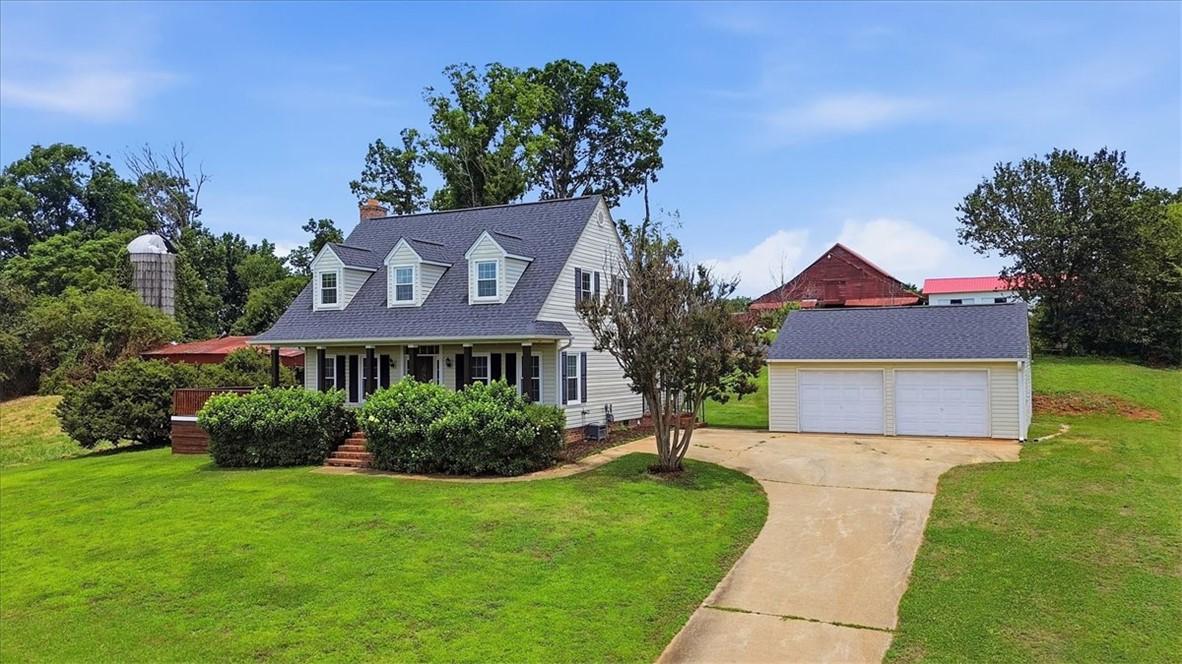 Image 2: A classic farmhouse with a detached garage sits am