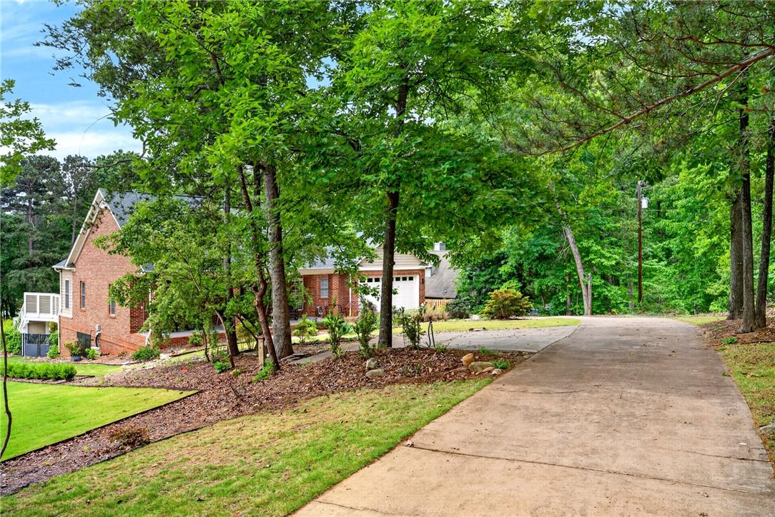 Image 3: Mature trees and lush landscaping frame this invit