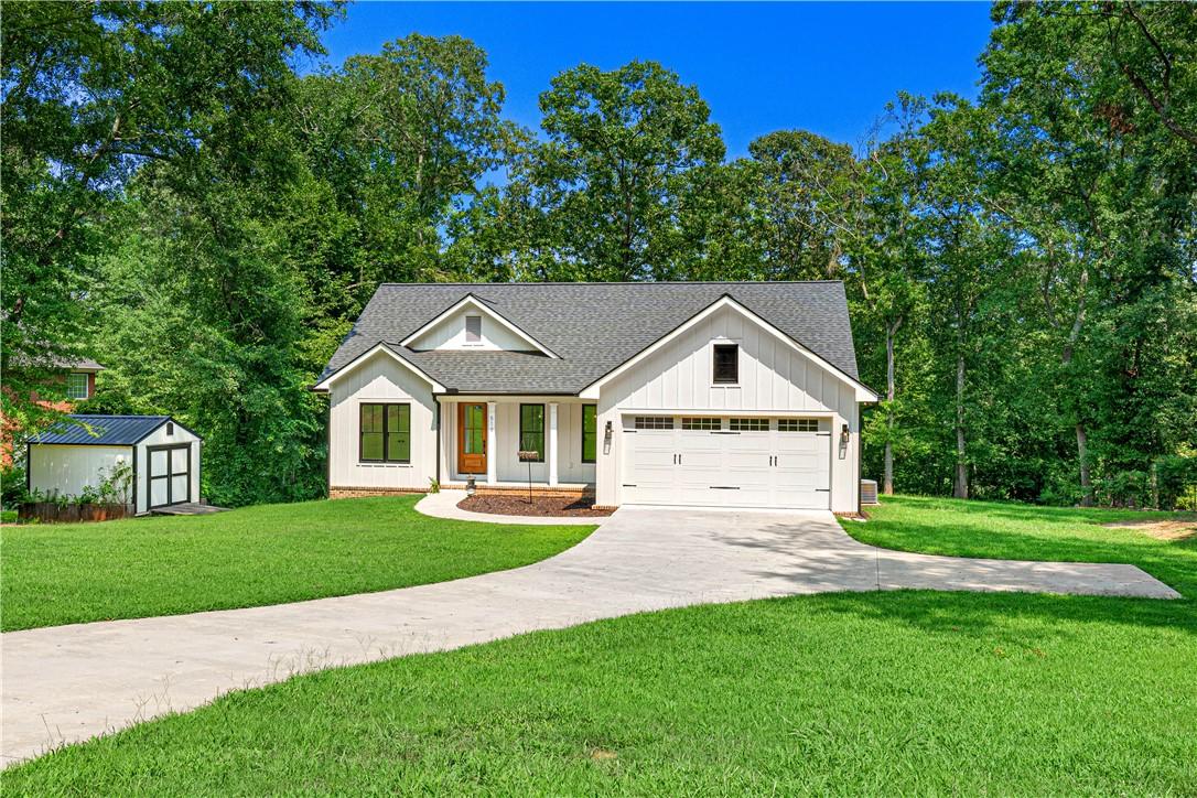 Image 2: A graceful white farmhouse-style home is complemen