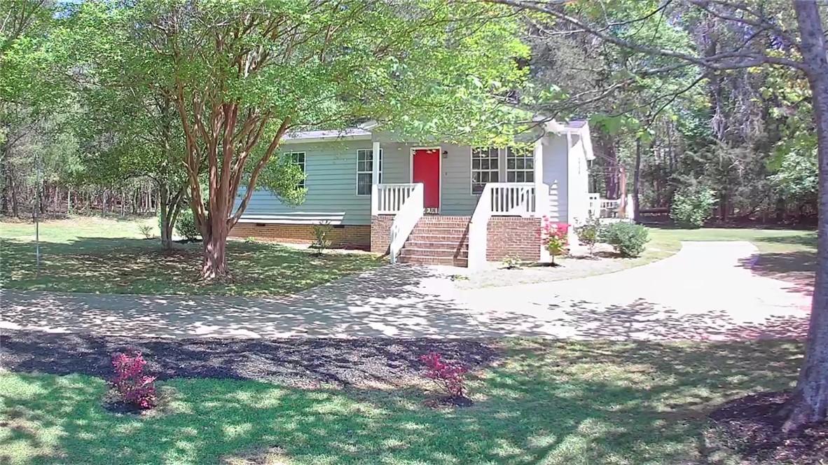 Image 3: This charming home features a vibrant red door, in