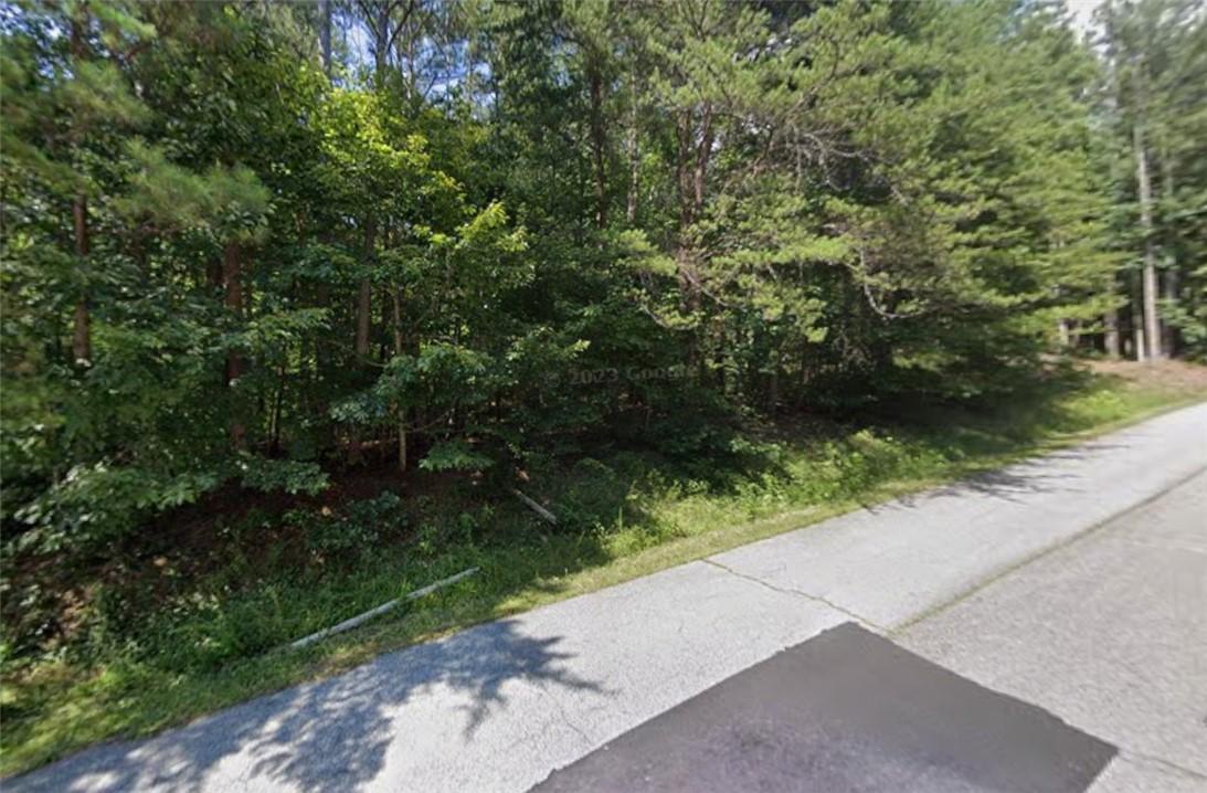 Image 1: Mature trees line this expansive lot, offering a p