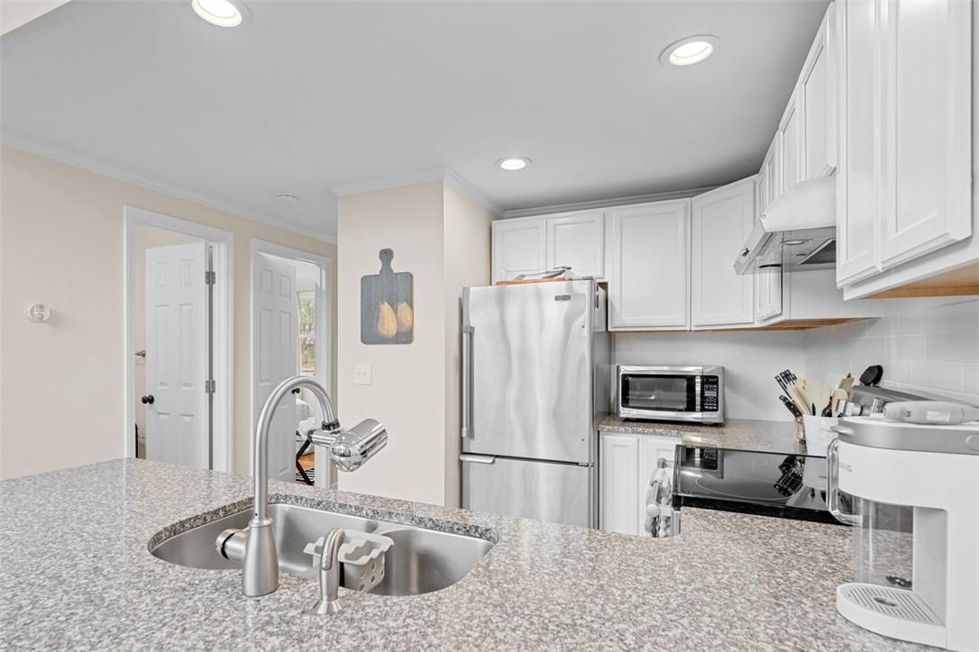Image 3: This bright kitchen features white cabinetry and s