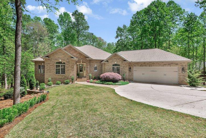 Image 1: This charming brick home is nestled among lush tre