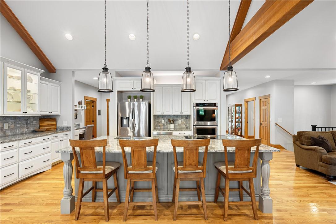 Image 4: A gourmet kitchen boasts high ceilings, stone coun