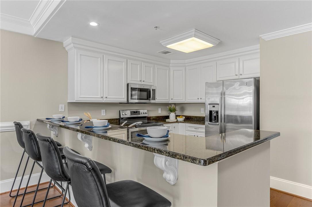 Image 4: White cabinetry, dark granite counters, and stainl