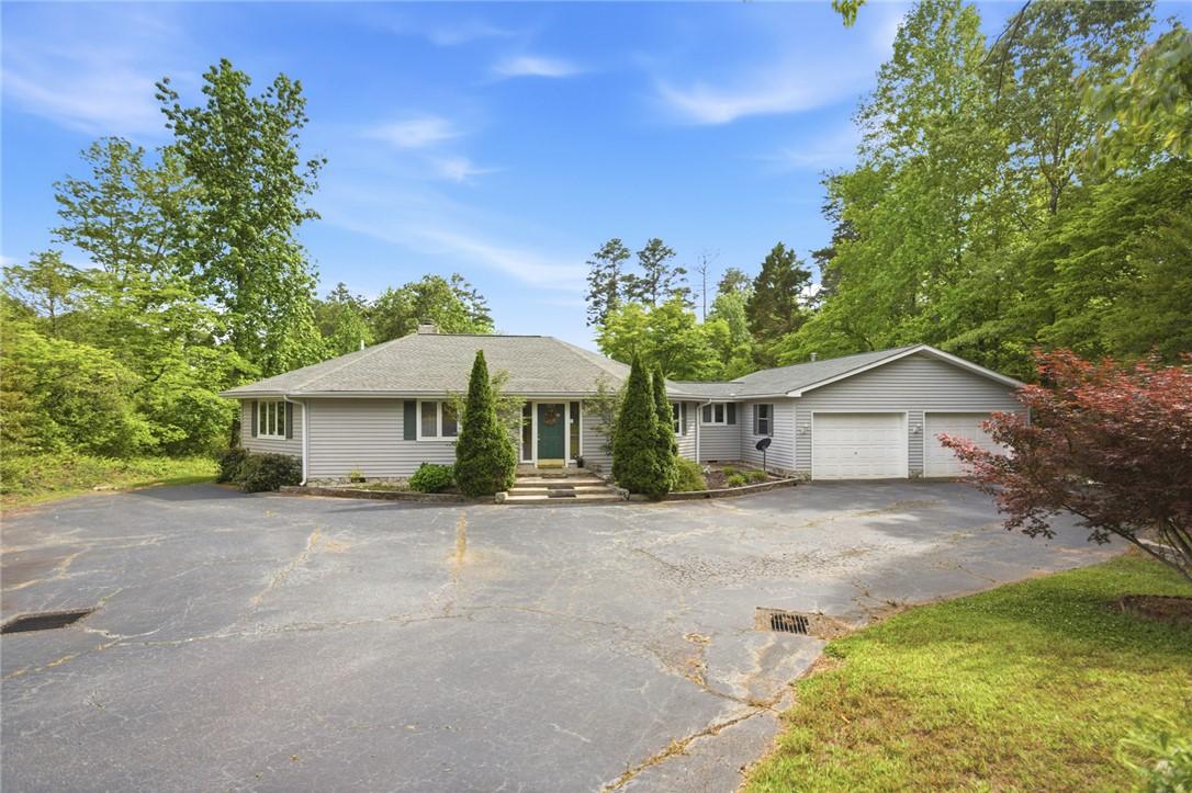 Image 1: This charming home features a paved driveway and a