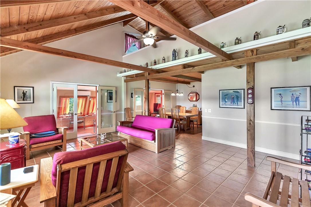 Image 4: Natural wood beams soar above a spacious living ar