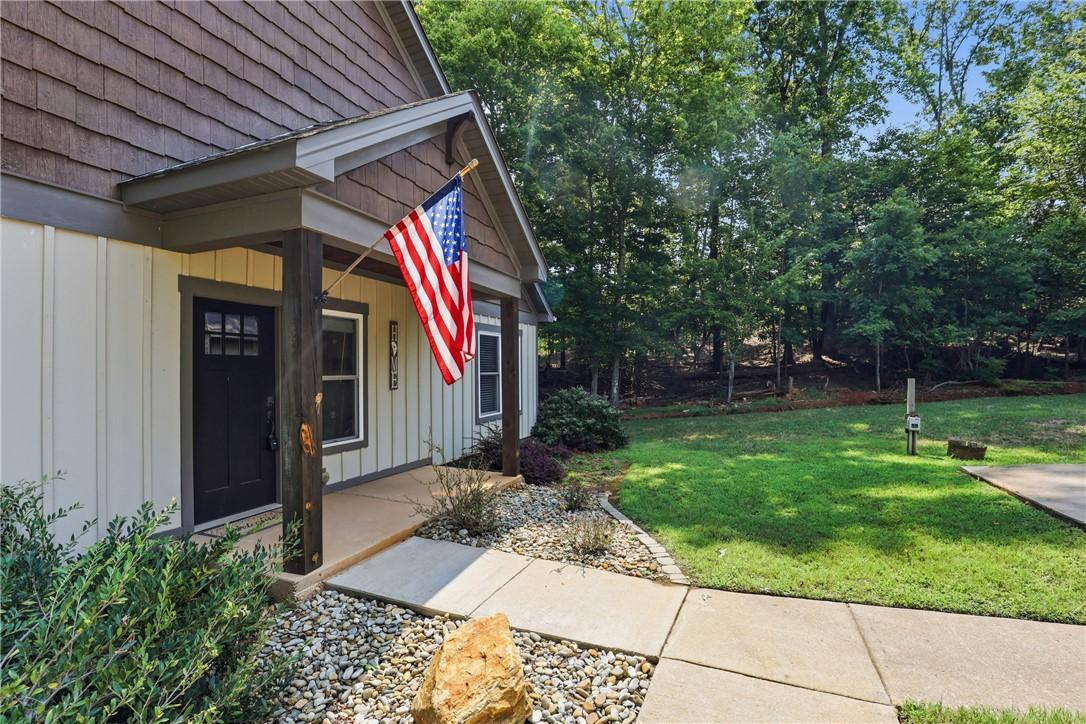Image 2: An inviting front porch welcomes you, framed by na