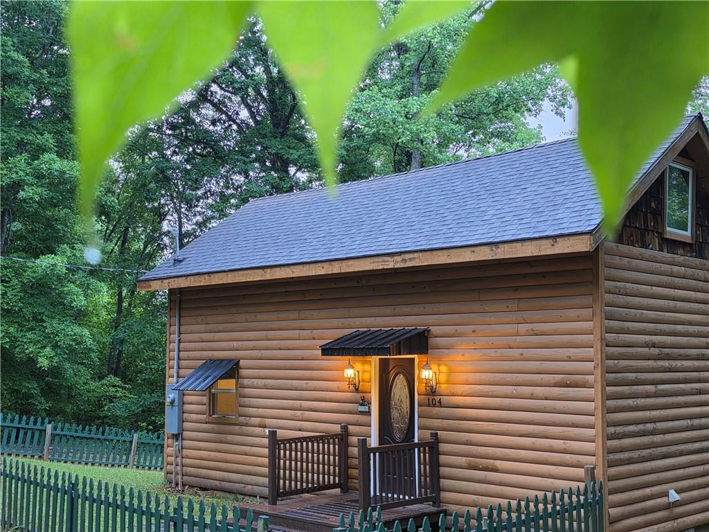 Image 1: This charming retreat features log siding, a welco