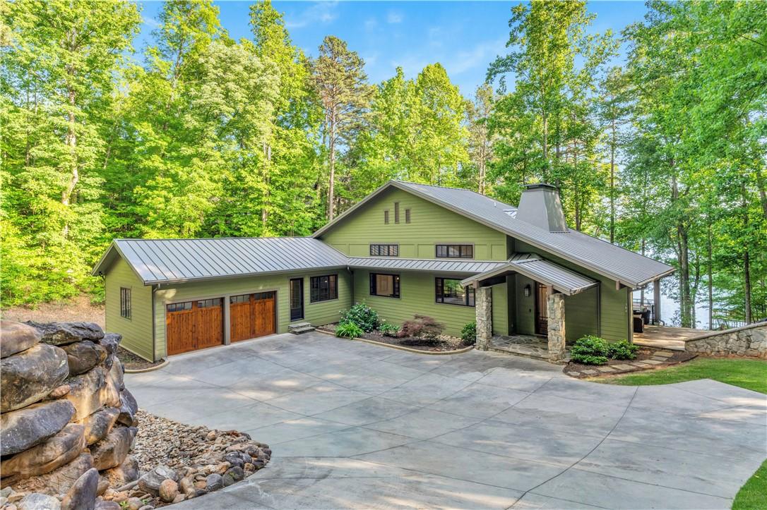 Image 1: This verdant home features a spacious driveway and