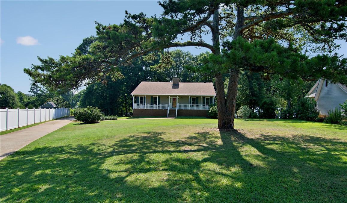 Image 2: Mature trees frame a charming home with a welcomin