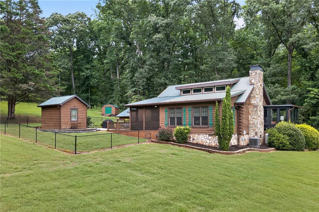 Image 3: A charming log home with a stone chimney and scree