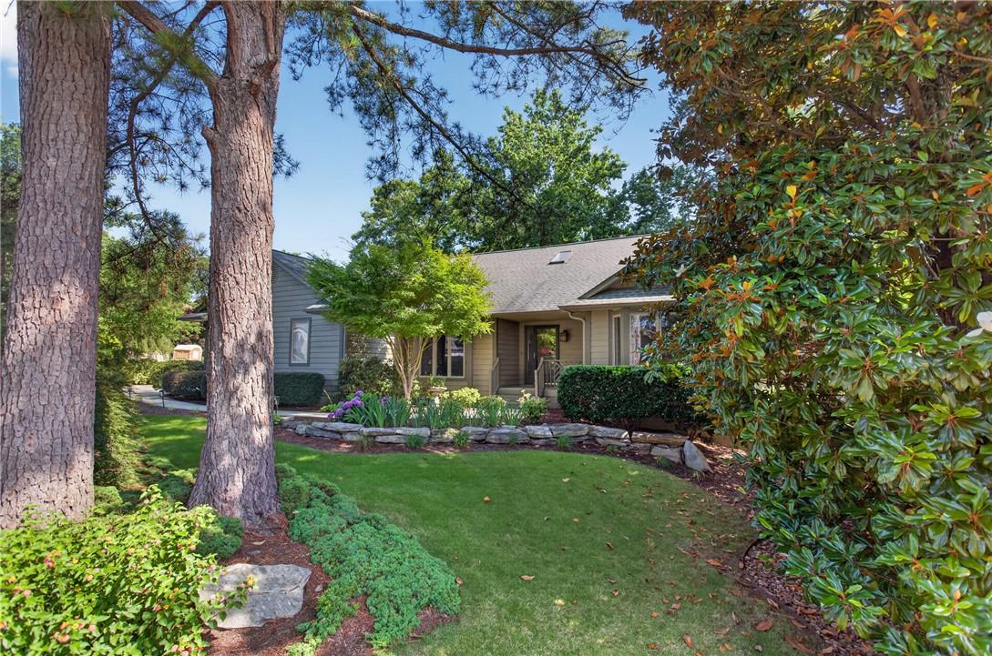 Image 2: Mature trees frame a charming home, enhancing its
